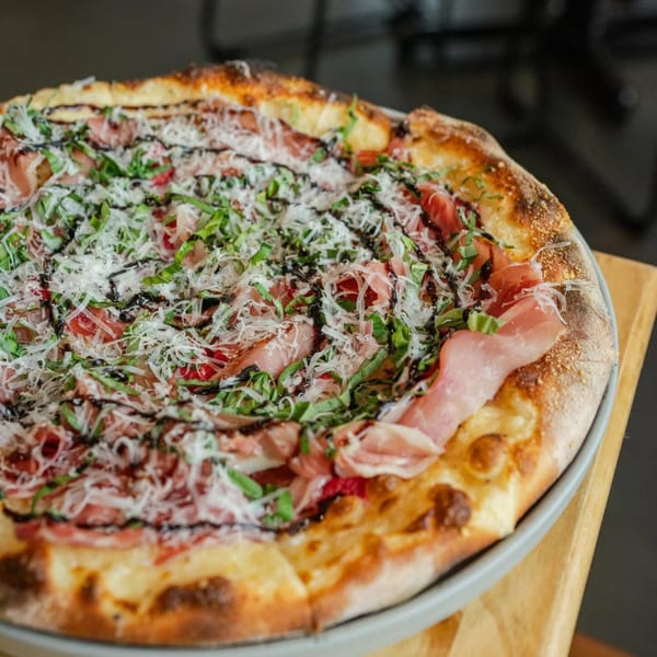 A New-American pizza from Ednas Market & Grille, topped with prosciutto, basil, parmesan, and balsamic glaze.