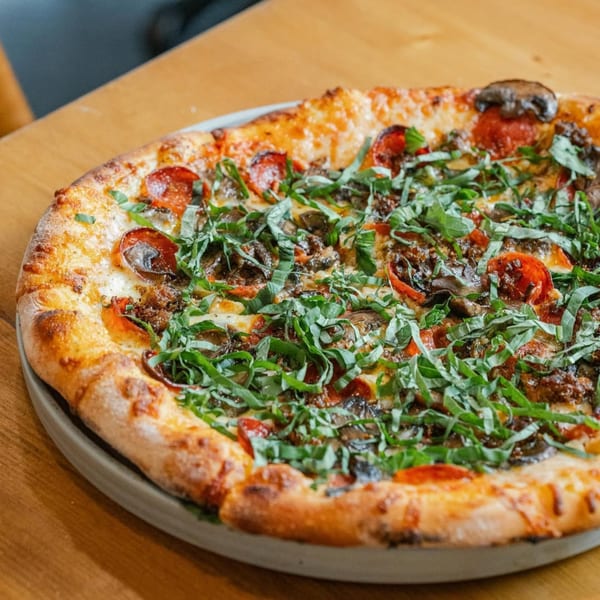 A New American pizza from Ednas Market & Grille, topped with pepperoni, mushrooms, and fresh basil.