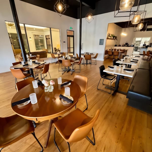 The interior of Ednas Market & Grille features modern tables, brown chairs, and warm lighting.