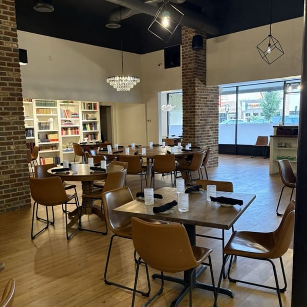 Ednas Market & Grille dining room with tables, chairs, brick columns, and a bookshelf wall.