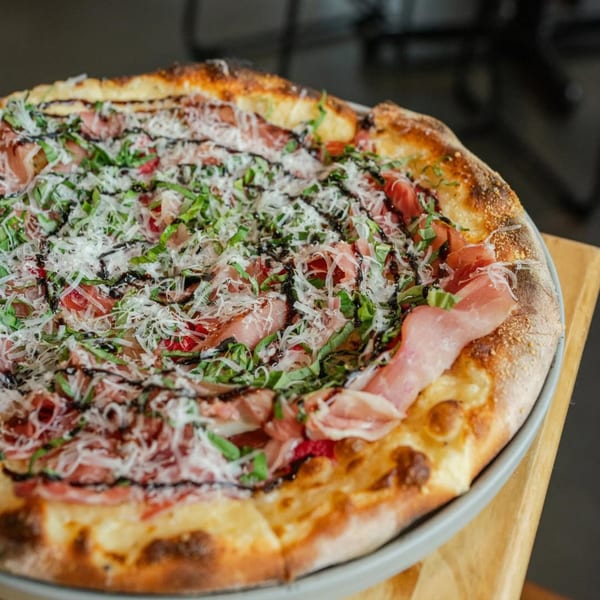 New-American pizza from Ednas Market & Grille, topped with prosciutto, basil, and balsamic glaze.